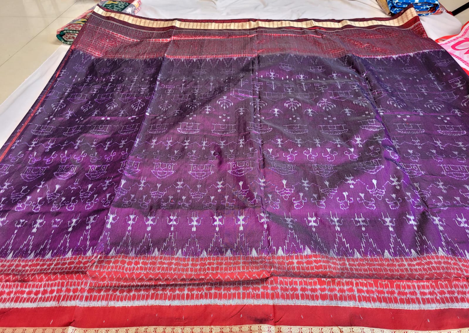 A purple and maroon saree featuring a house and little man body pattern, complemented by a pallu with exclusive silk and polyester designs.